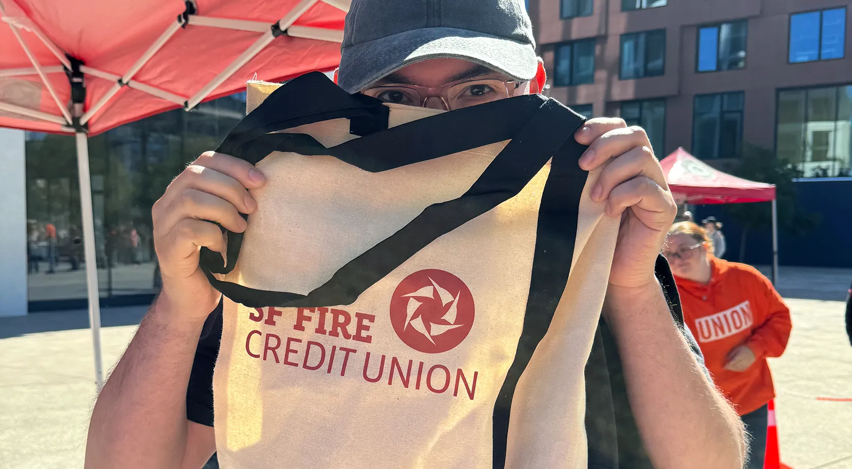 Man holding up a SF Fire tote bag at a community event