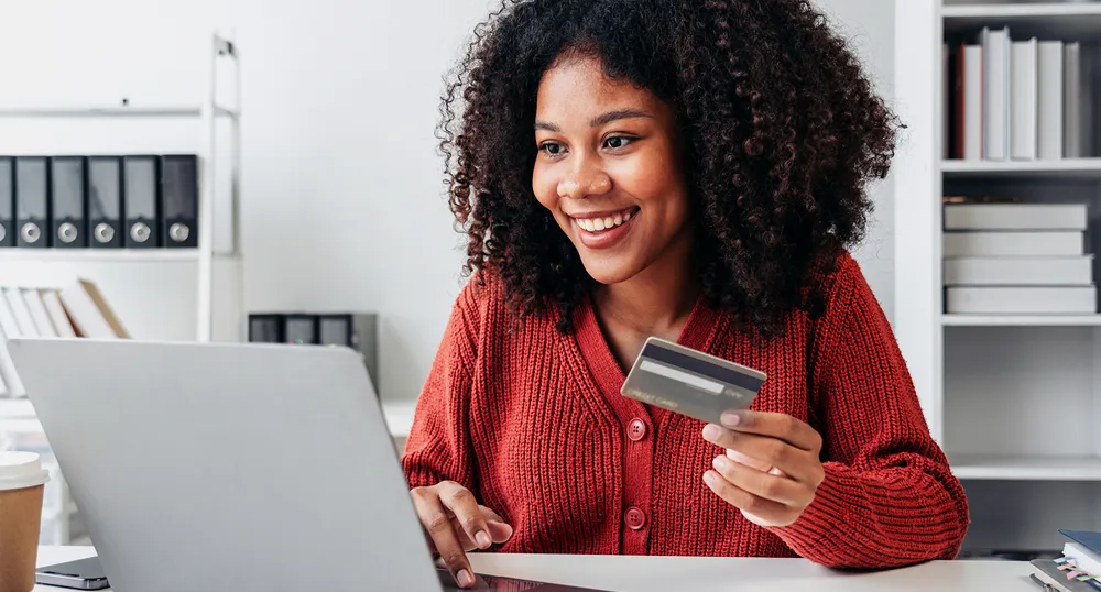 African American woman on laptop with Visa card in hand