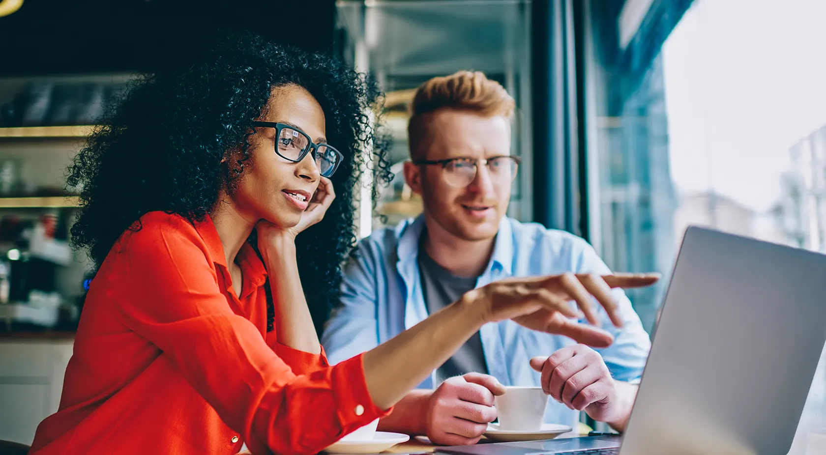 Professionally dressed woman and man discussing something on the laptop in cafe