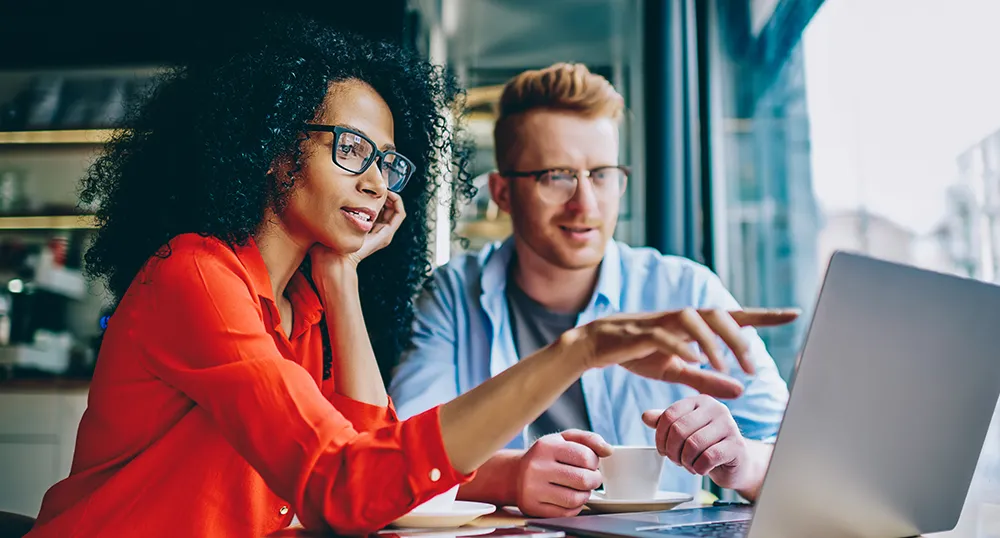 Professionally dressed woman and man discussing something on the laptop in cafe