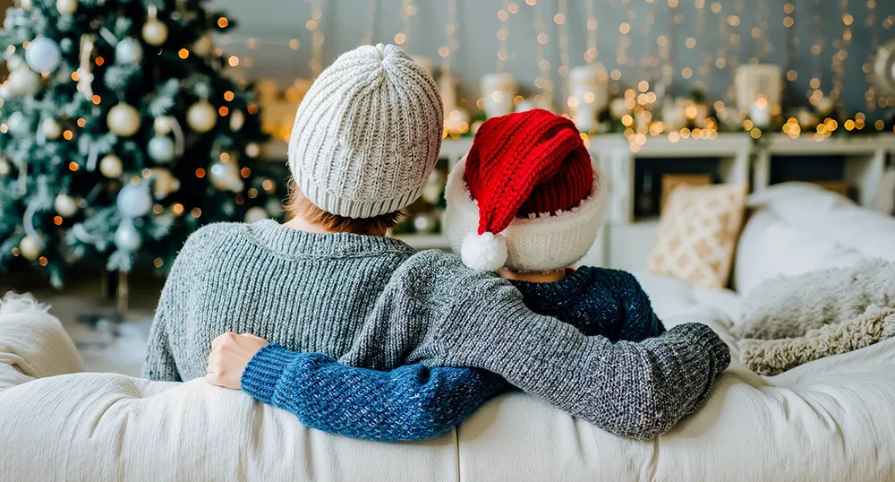 A couple siting on their couch looking at the Christmas tree