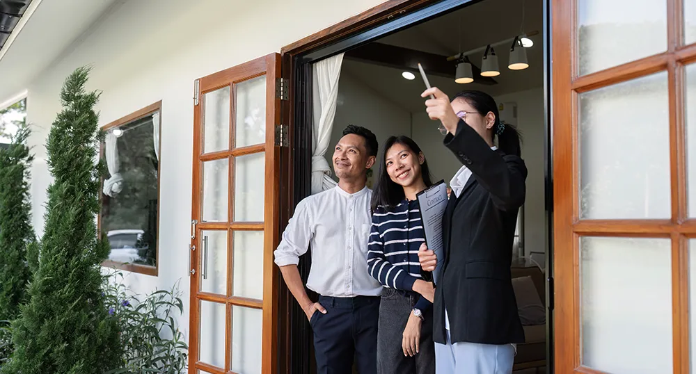 Asian couple surveying a home while realtor points out something