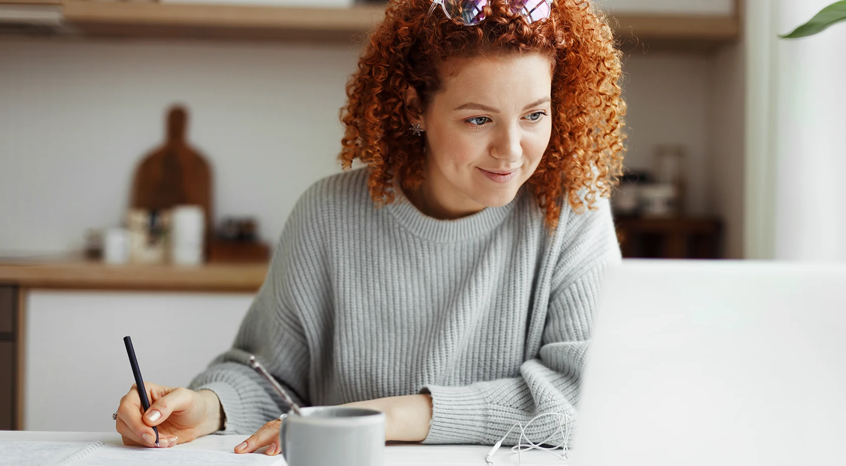 Woman looking at laptop taking notes