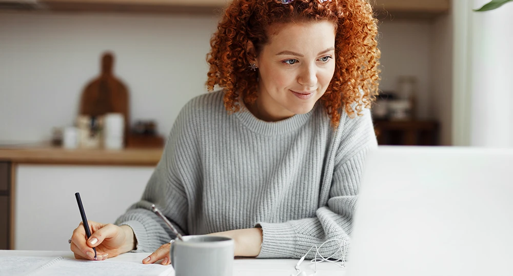 Woman looking at laptop taking notes