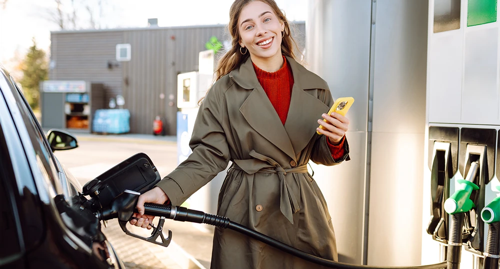 Women filling gas on her phone