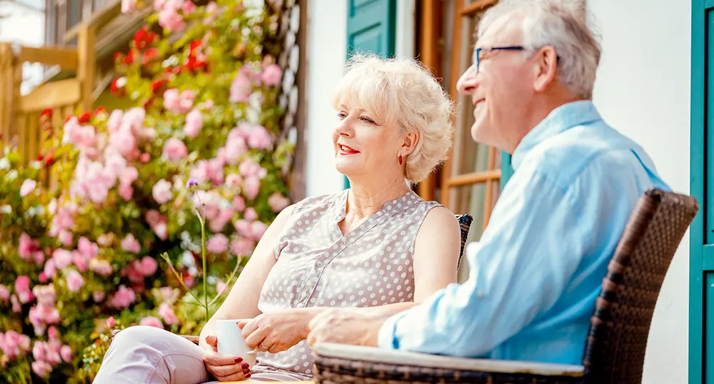 elderly couple sitting outside their home