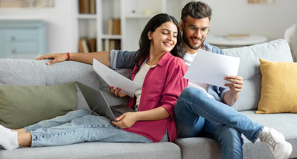 Couple Sitting on sofa reading paper
