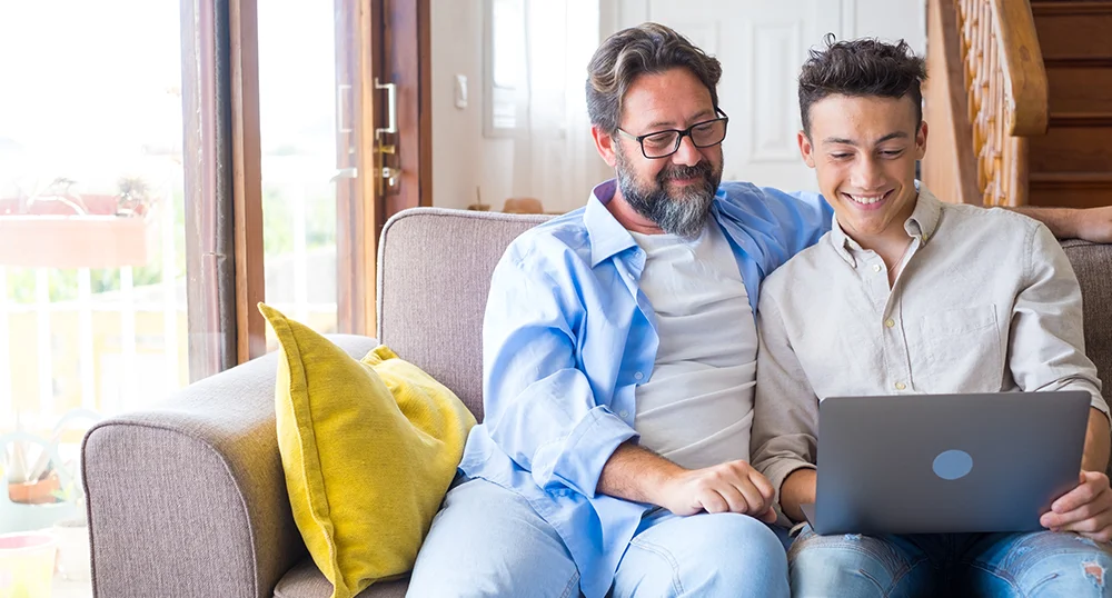Father helping son on laptop