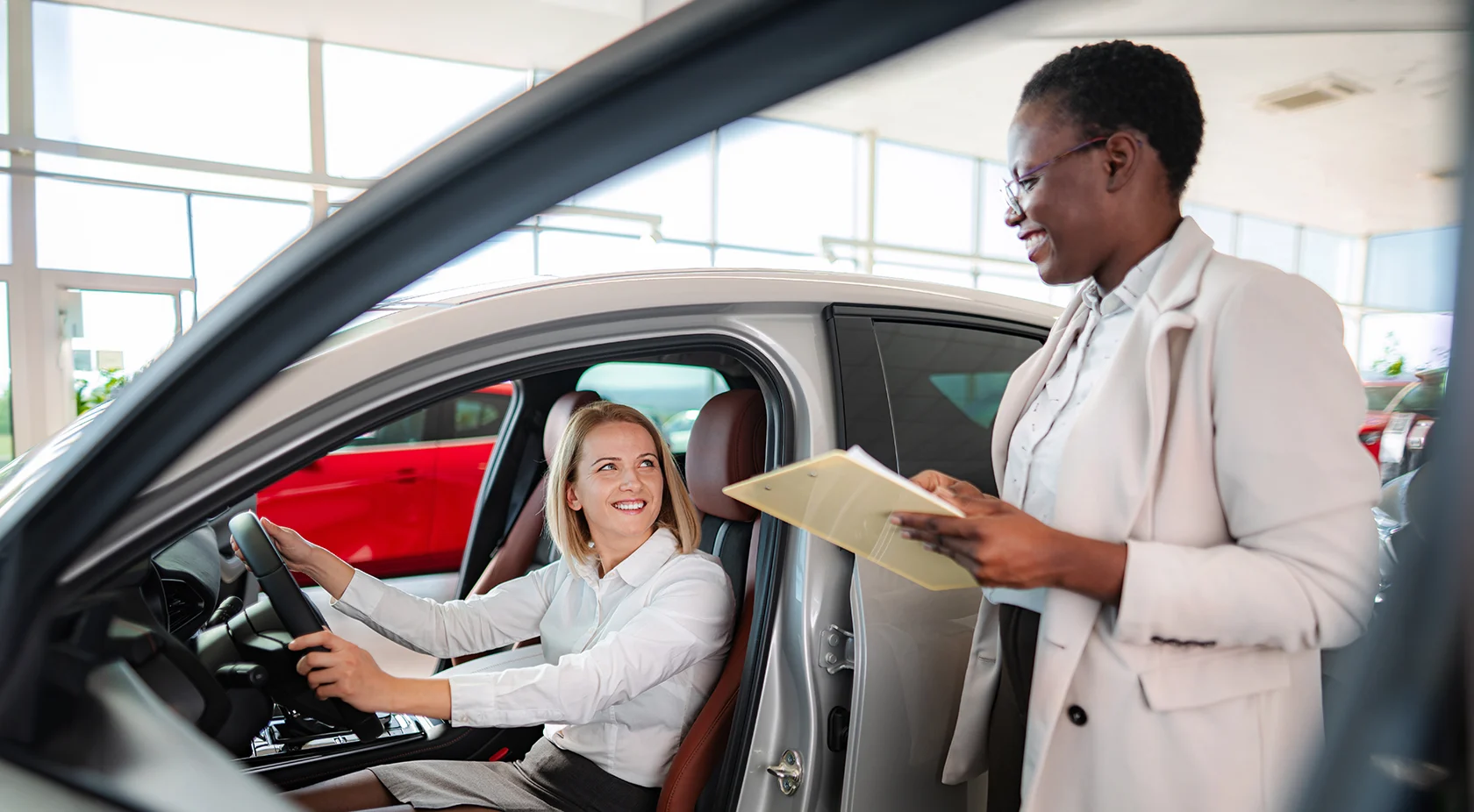 Woman in car talking to car salesperson in showroom