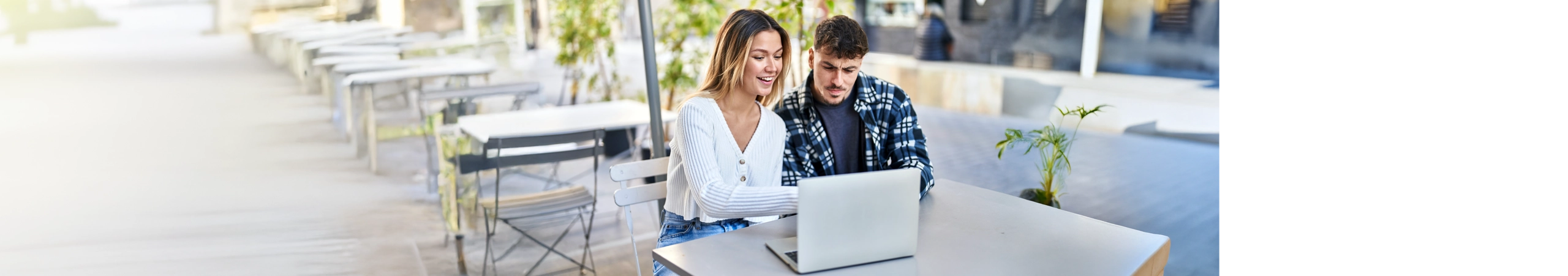 couple sitting outdoors with laptop