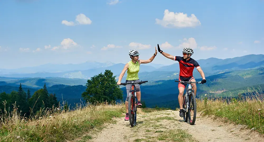 two people riding mountain bikes through the hills giving a high five