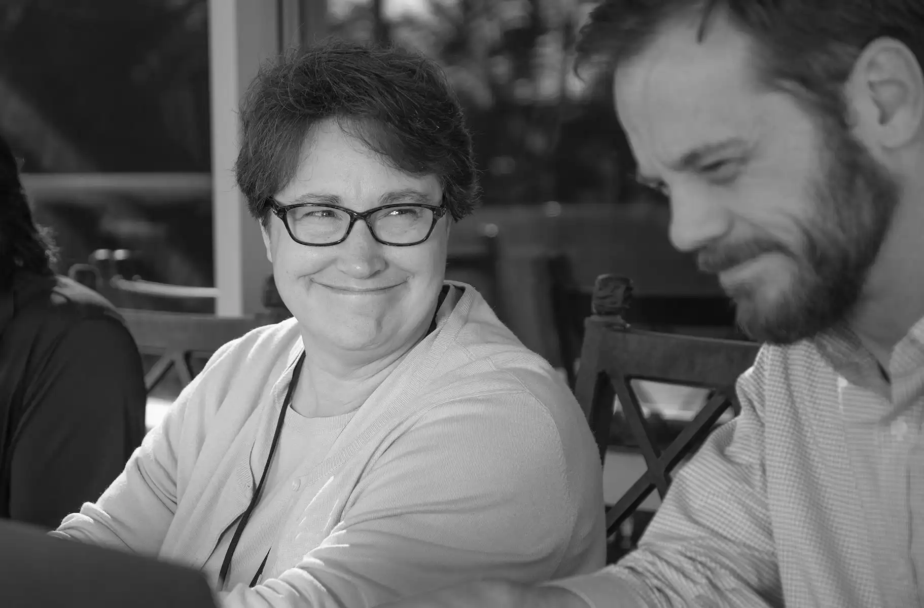 Bespectacled woman stares joyfully to a point off camera.