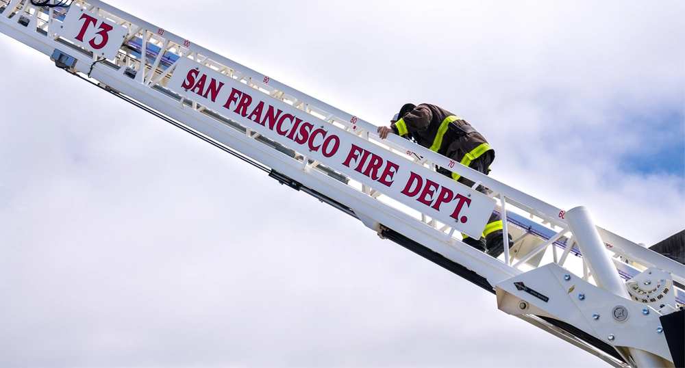 SFFD firefighter going up a truck ladder
