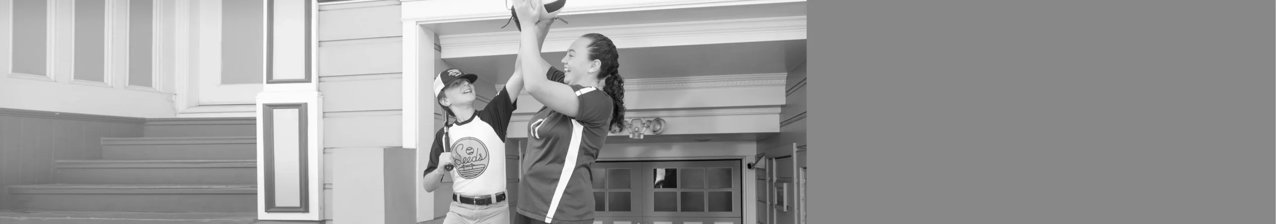 Siblings play with a volleyball in front of their garage.